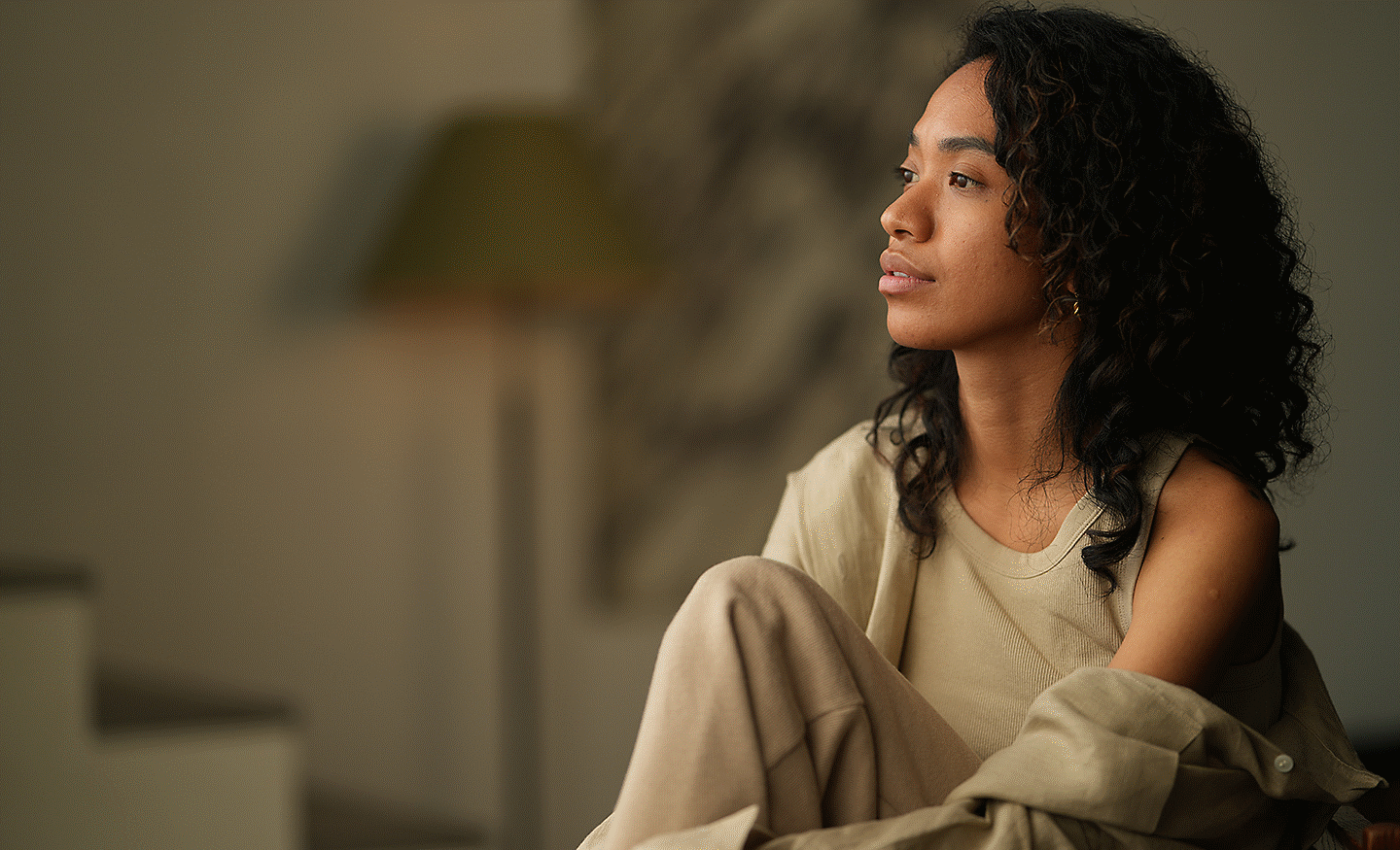 Indoor portrait of a woman sitting by a window with soft lighting and shallow depth of field.