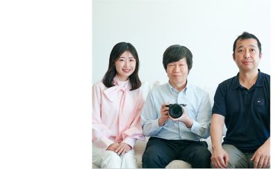 Mr. Abe, Mr. Suzuki, and Mr. Hatanaka sit side by side on the sofa in this group photo. Mr. Suzuki is holding a full-size mirrorless SLR camera “α7C II”.