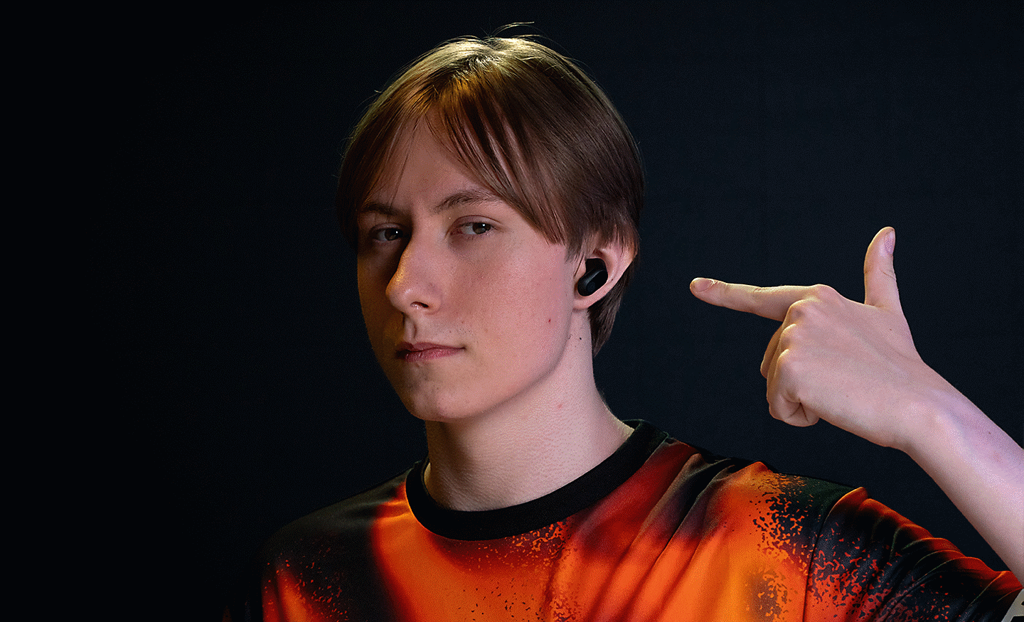 Profilna slika Chronicla, ki z roko kaže na črne slušalke INZONE Buds v svojih ušesih