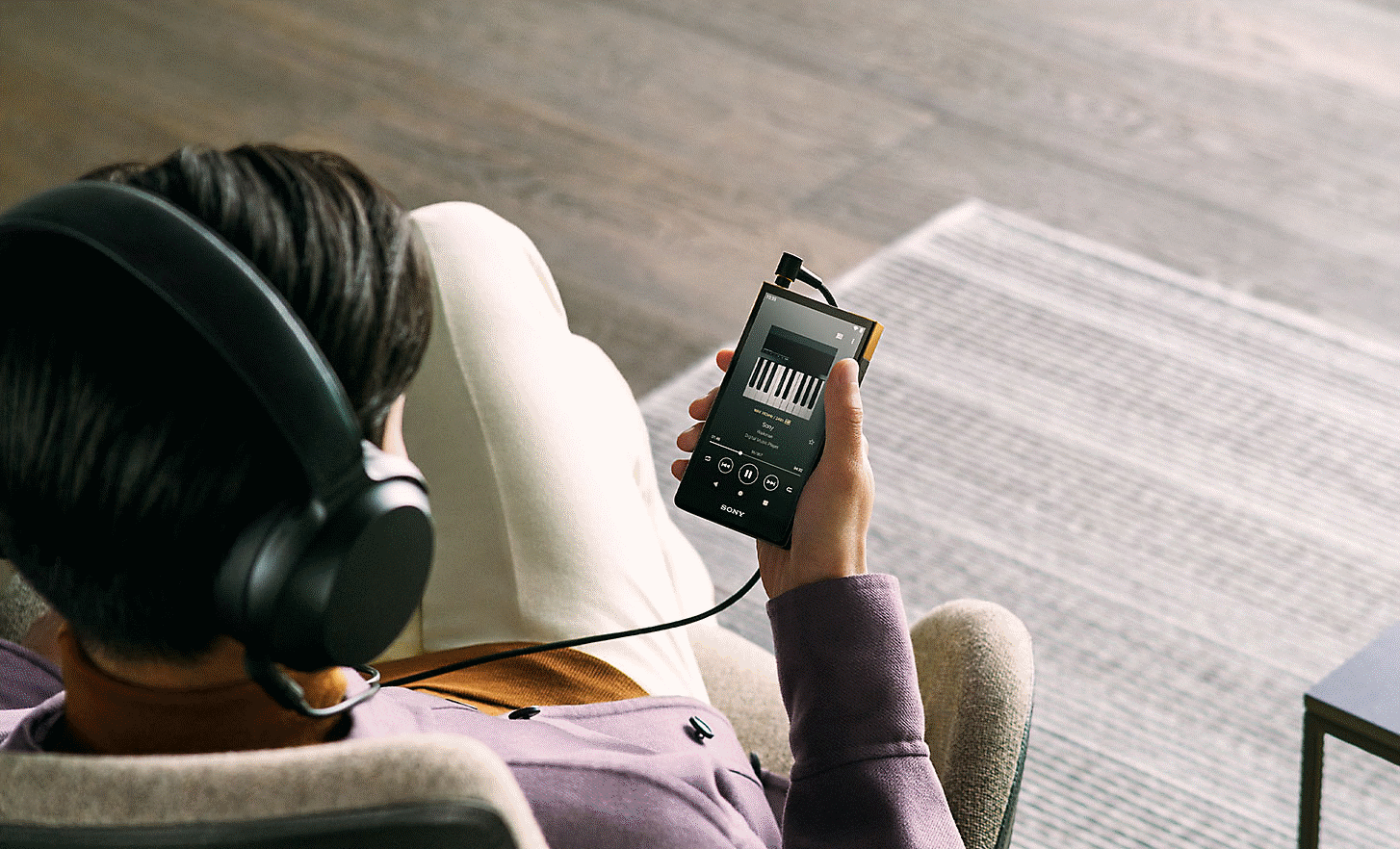 使用者戴著 Sony 耳機手持 NW-ZX707 聽音樂的影像。