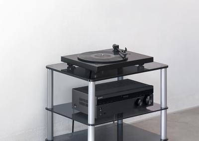 Bluetooth vinyl record player and an amplifier on a glass table in a living room