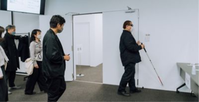 Employees watching lead user with white cane is walking in the conference room