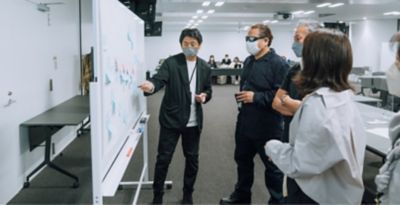 Employees gather in front of a whiteboard and having a conversation