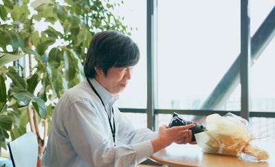 A bouquet of flowers is placed in front of Mr Suzuki setting up the camera