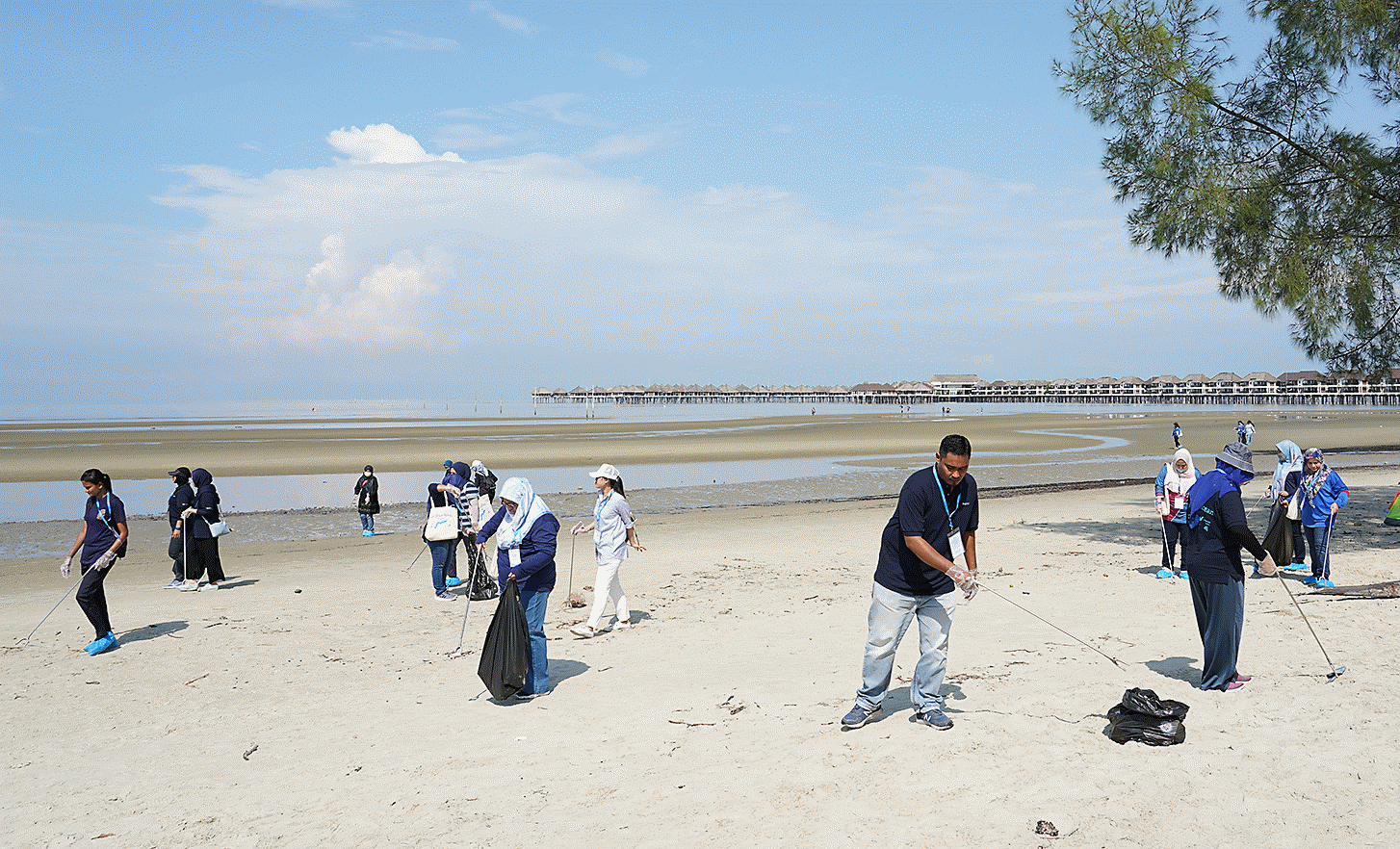 Fotografía que muestra a los empleados del sitio de Malasia participando en una actividad de limpieza de playa