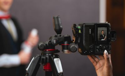 LCD 모니터의 피사체를 그리드 라인에 맞도록 조정하고 삼각대에 고정된 토토사이트 썸를 잡고 있는 이미지 예시