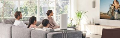 An image of a family of four watching TV while relaxing on the sofa.