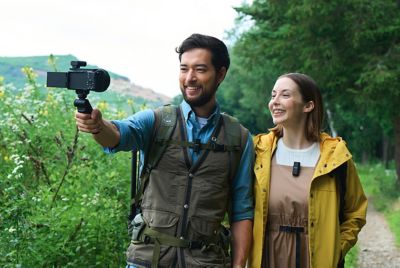 Fotografía en la que se muestra a un hombre y una mujer con micrófonos puestos sonriendo a la cámara que tiene un receptor acoplado