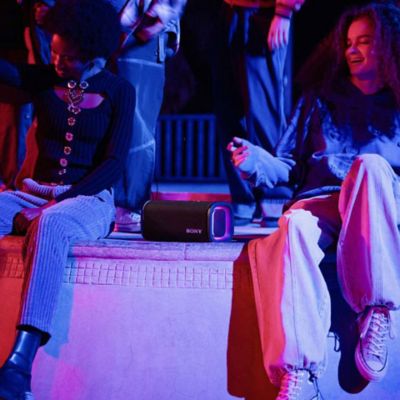 Jóvenes escuchando música con ULT FIELD 5, que convierte la iluminación en violeta en un parque de patinetas por la noche.