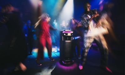 Imagen del parlante para fiestas ULT TOWER 10 y un grupo de jóvenes bailando en un lugar lleno de gente