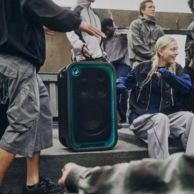 Gente disfrutando de la música en una fiesta en una azotea, con el ULT TOWER 7 en el centro de la reunión.
