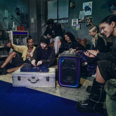 En una fiesta en un espacio interior, el ULT TOWER 5 está entre un DJ y una multitud de personas disfrutando de la música.